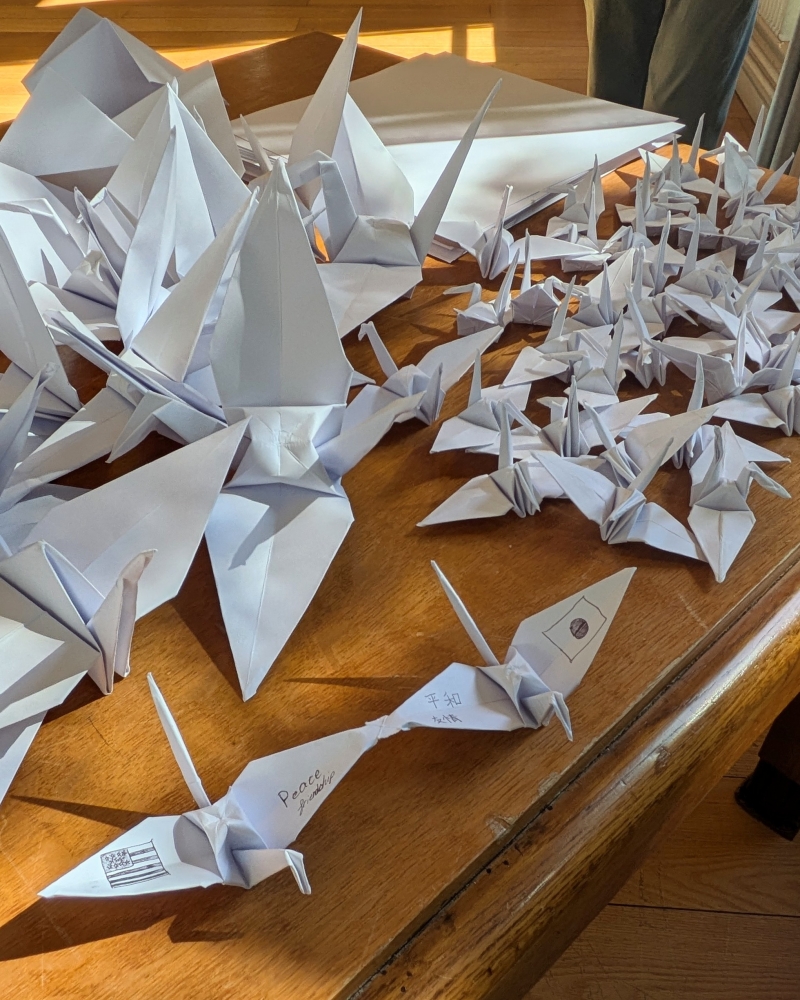 Photo de nombreux origamis grue faits par les visiteurs, et devant, un origami de deux grues jointes par l'aile (les drapeaux des Etats-Unis et du Japon, ainsi que les mots Peace et Friendship sont inscrits sur les ailes)