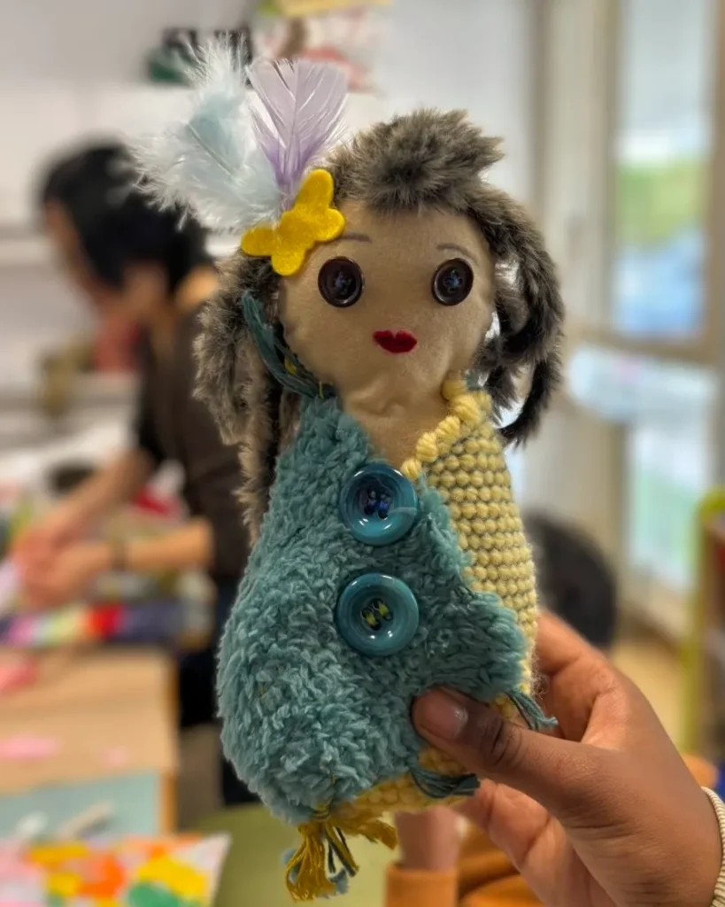 Une poupée avec des plumes et un ruban sur la tête.